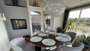 A dining area with a round table, grey upholstered chairs, and a chandelier. - 5 Star Holiday Home in Skummeslovsstrand (Skummesloevsstrand)