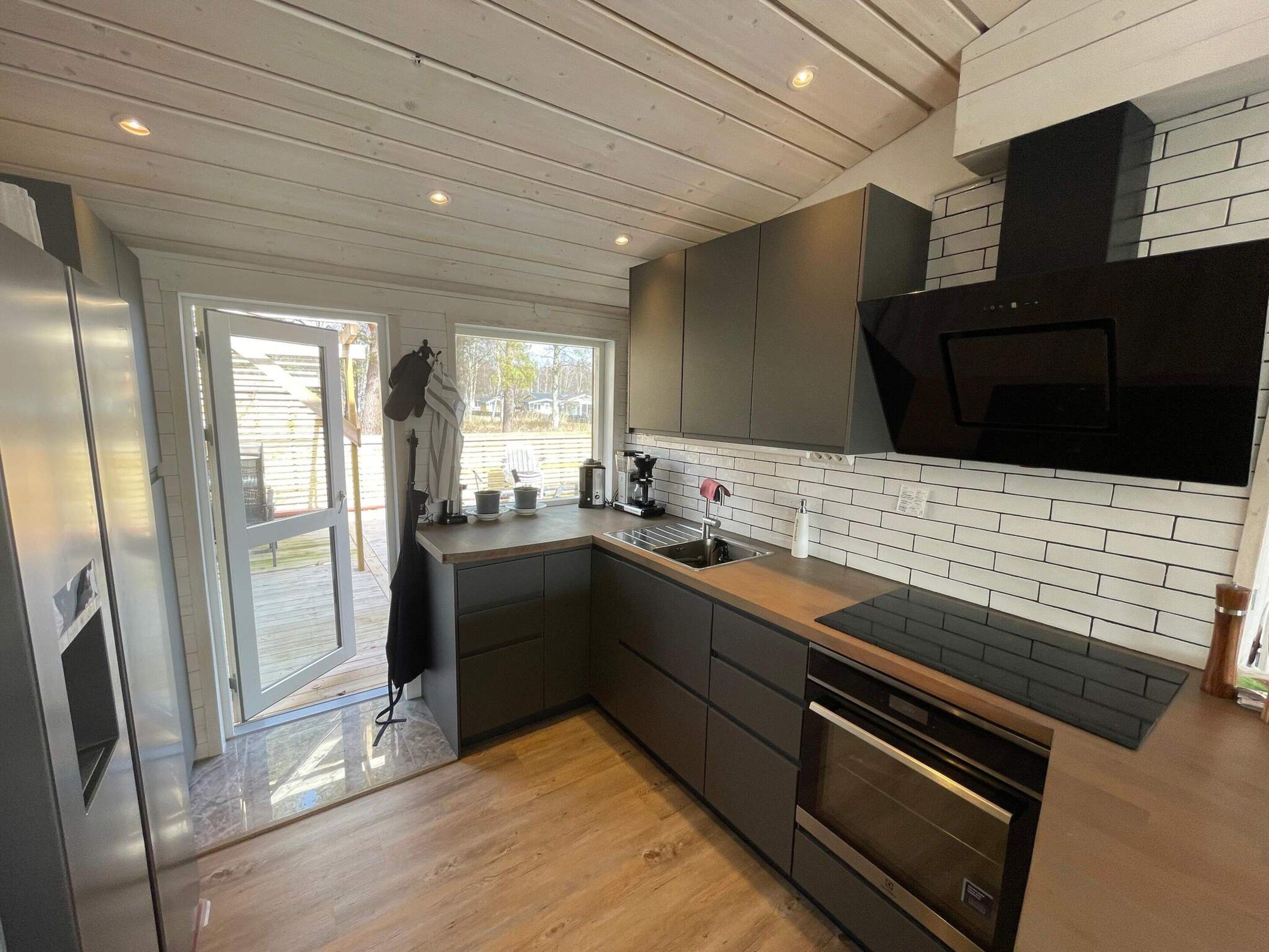 A modern kitchen with a built-in oven, a sink, and a window overlooking a deck.