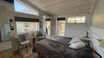 A bedroom with a large bed, a chair, a desk, and a window.