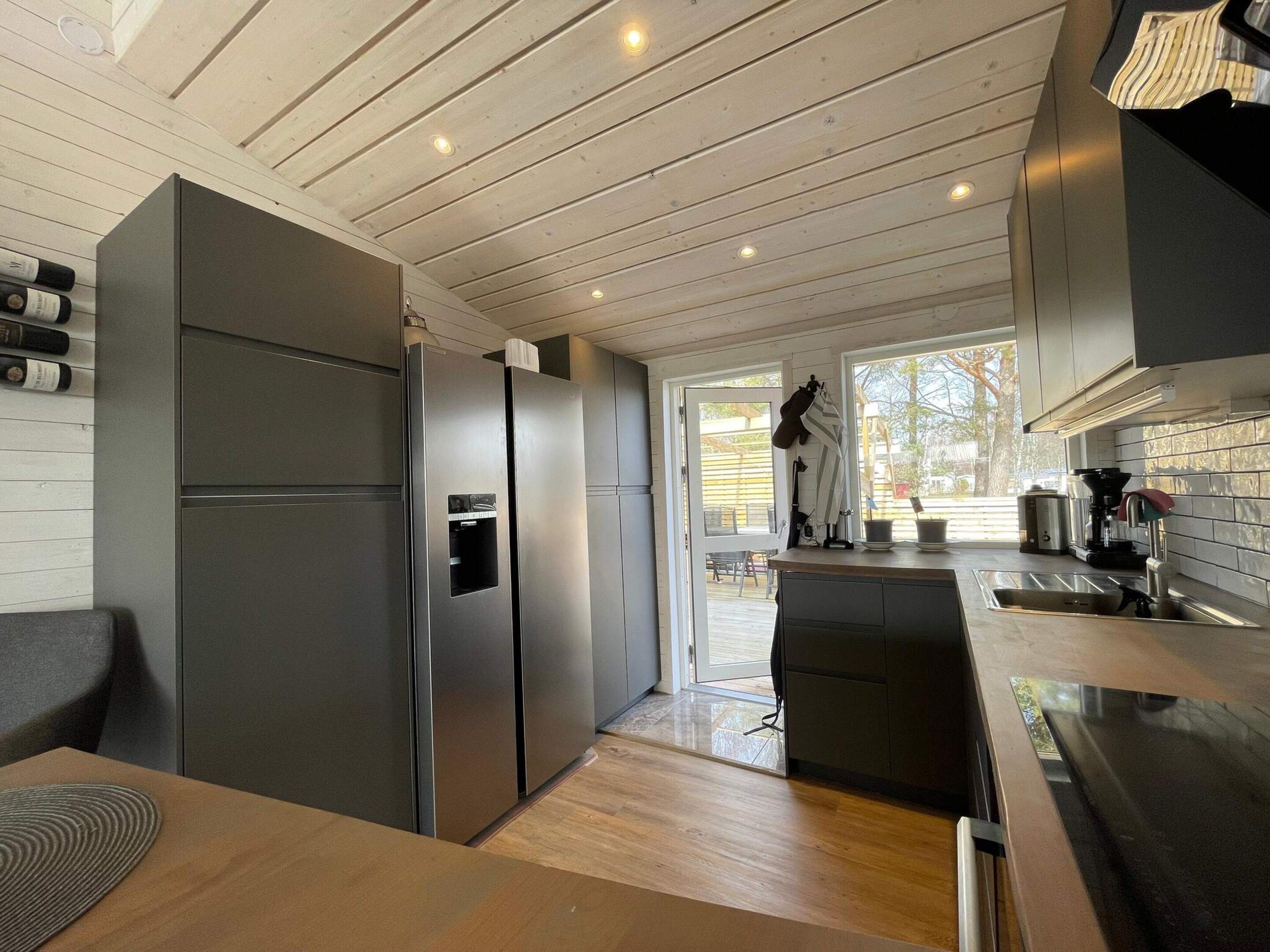 A modern kitchen with a built-in stainless steel refrigerator, a coffee machine, and a dining area with a wooden table.