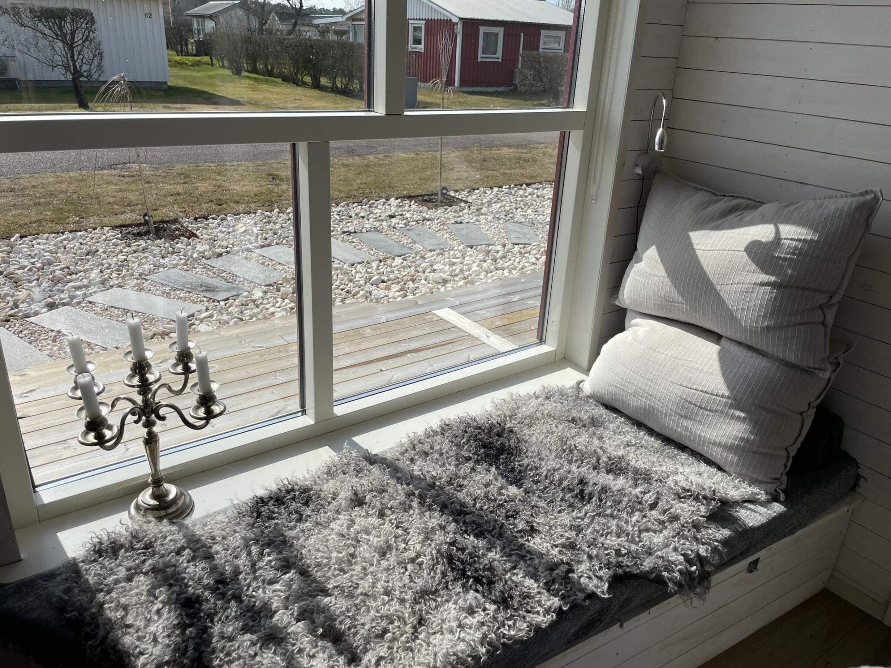 A room with a bench seat, a candelabra with candles, and a view of a residential area through a window.