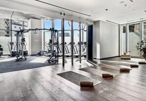 A modern gym with exercise equipment, mats, and a large glass wall. - The Skyline Grand | Panoramic Views + Free Parking! (Melbourne)