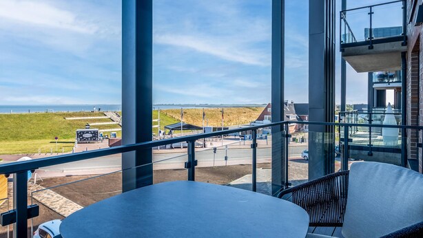 A balcony with a view of the sea, a table, and chairs. - The View B10 AHOI - Sea view, balcony, 2nd floor, shared. (Dagebüll)