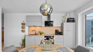 A modern kitchen with a round dining table, grey cabinets, and a large window. - The View G01 Licht-Luft-Ebbe und Flut - Balcony, Barbecue, Parking Space (Dagebüll)