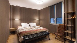 Ein modernes Schlafzimmer mit einem großen Bett, einer Bank, einem Holzhocker und einem eingebauten Kleiderschrank.