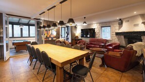 Ein geräumiges Wohnzimmer mit einem Holzesstisch, Ledersofas und einem Kamin.