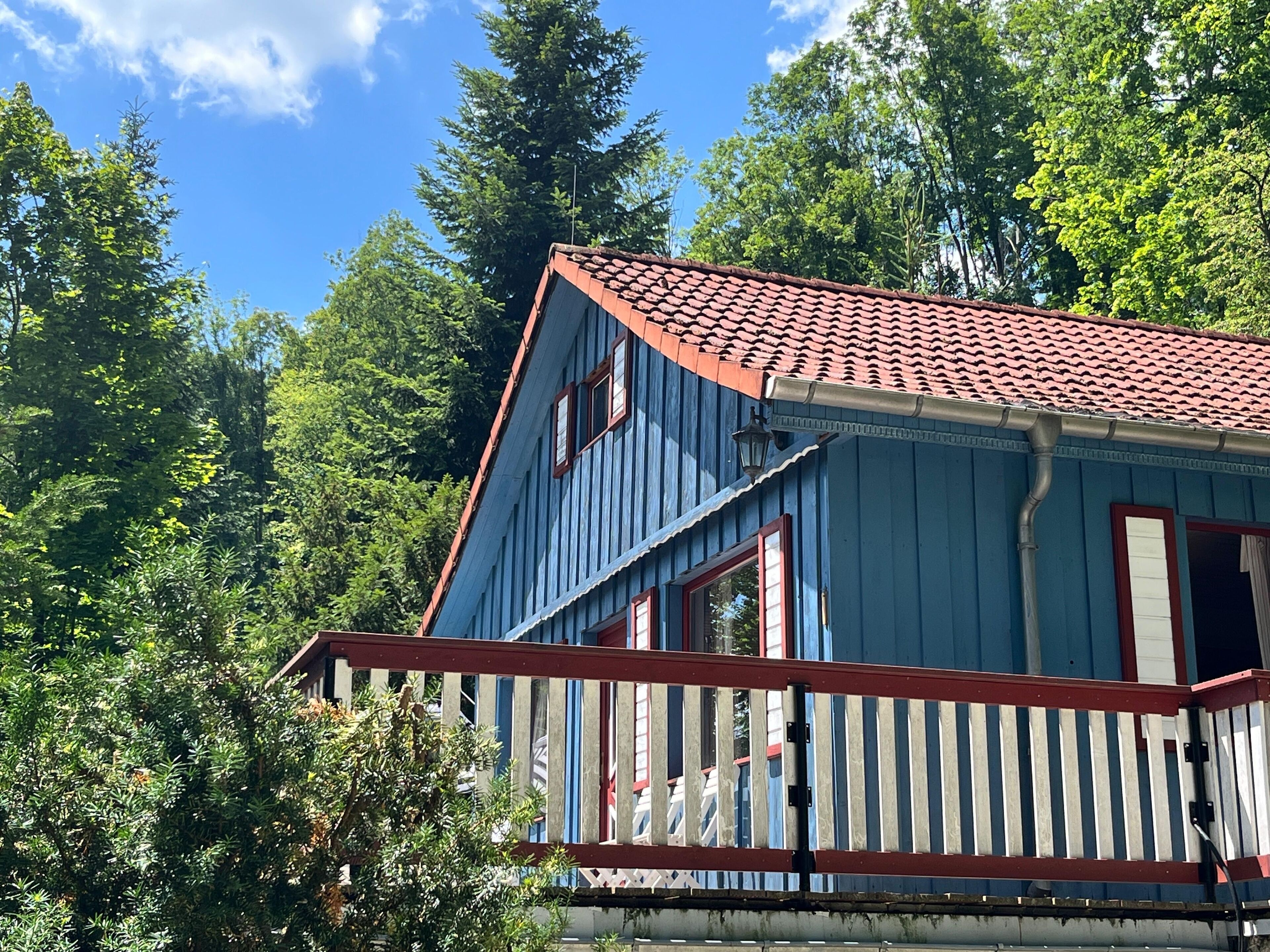 Una casa azul con techo rojo, rodeada de árboles.