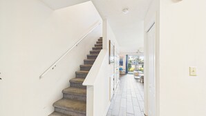 Um corredor estreito com escada carpetada que leva a um quarto com uma janela grande.