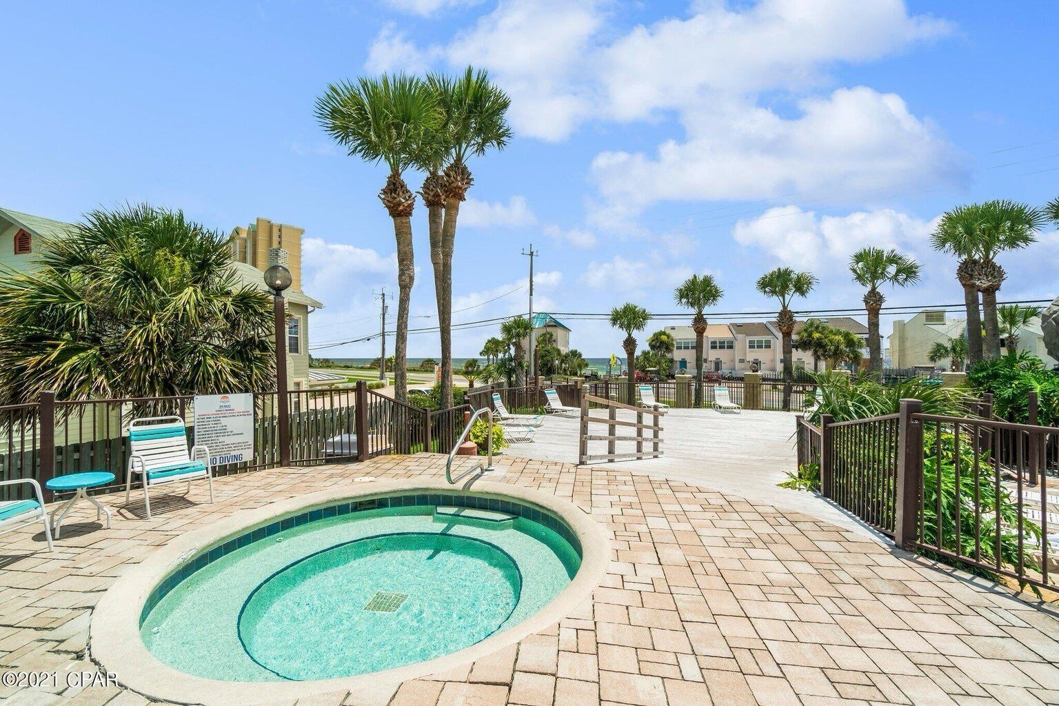 A pool area with a diving board, palm trees, and a clear sky.