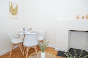 A dining area with a round table, white chairs, and a white vase with green plants. - Modern2 East12 Village Retreat Near Union Square (New York)