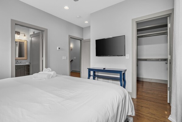 A hotel room with a large bed, a TV mounted on the wall, a walk-in closet, and a bathroom with a mirror and sink. - NEW! 10 min to Broadway! Welcome to Waverly Whimsy (Nashville)