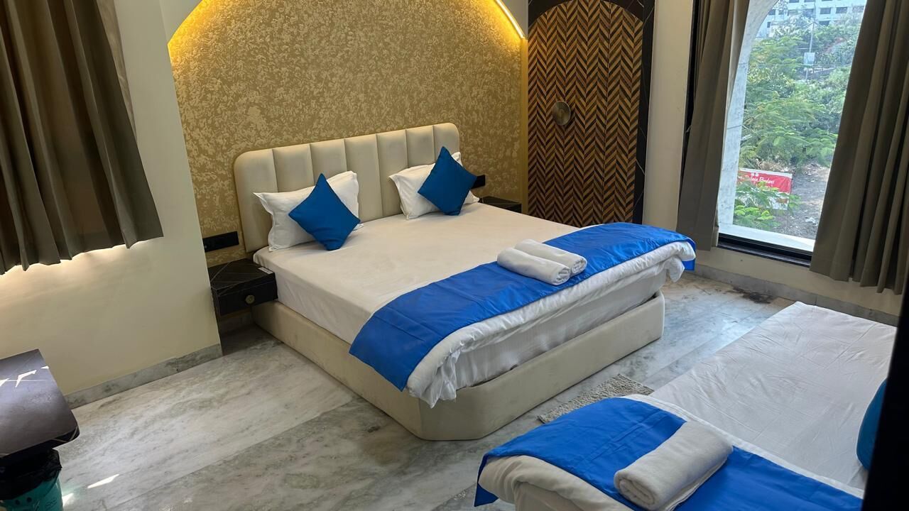 A hotel room with a large bed, a smaller bed, and a desk.