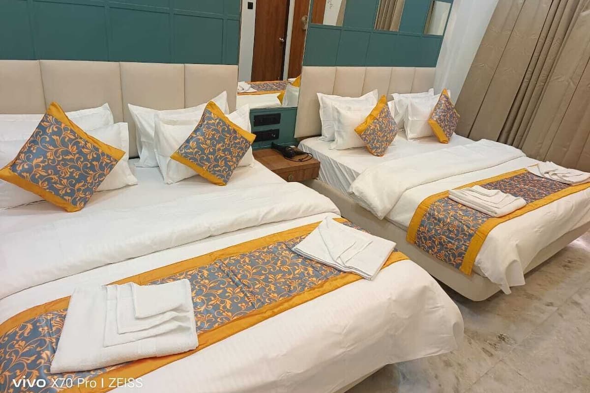 Ein Hotelzimmer mit drei Betten, jedes mit weißer Bettwäsche und Zierkissen.