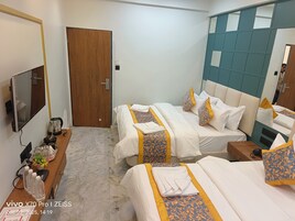 Habitación de hotel con dos camas, un escritorio de madera con hervidor, televisor y espejo.