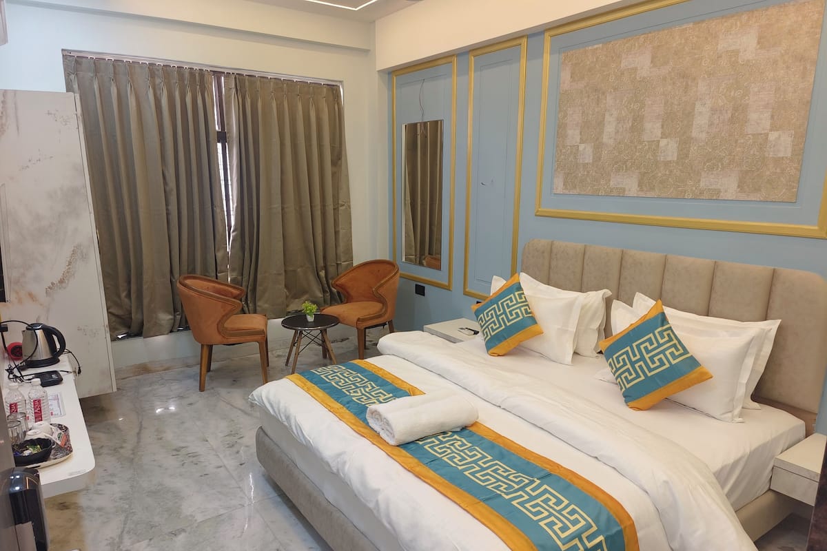 Ein Hotelzimmer mit einem Bett, zwei Stühlen, einem kleinen Tisch und einem Fenster mit Vorhängen.