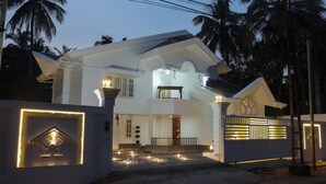 A two-story house with a balcony, a gated entrance, and a well-lit driveway. - Bloom Fort Villa  (Kannur)