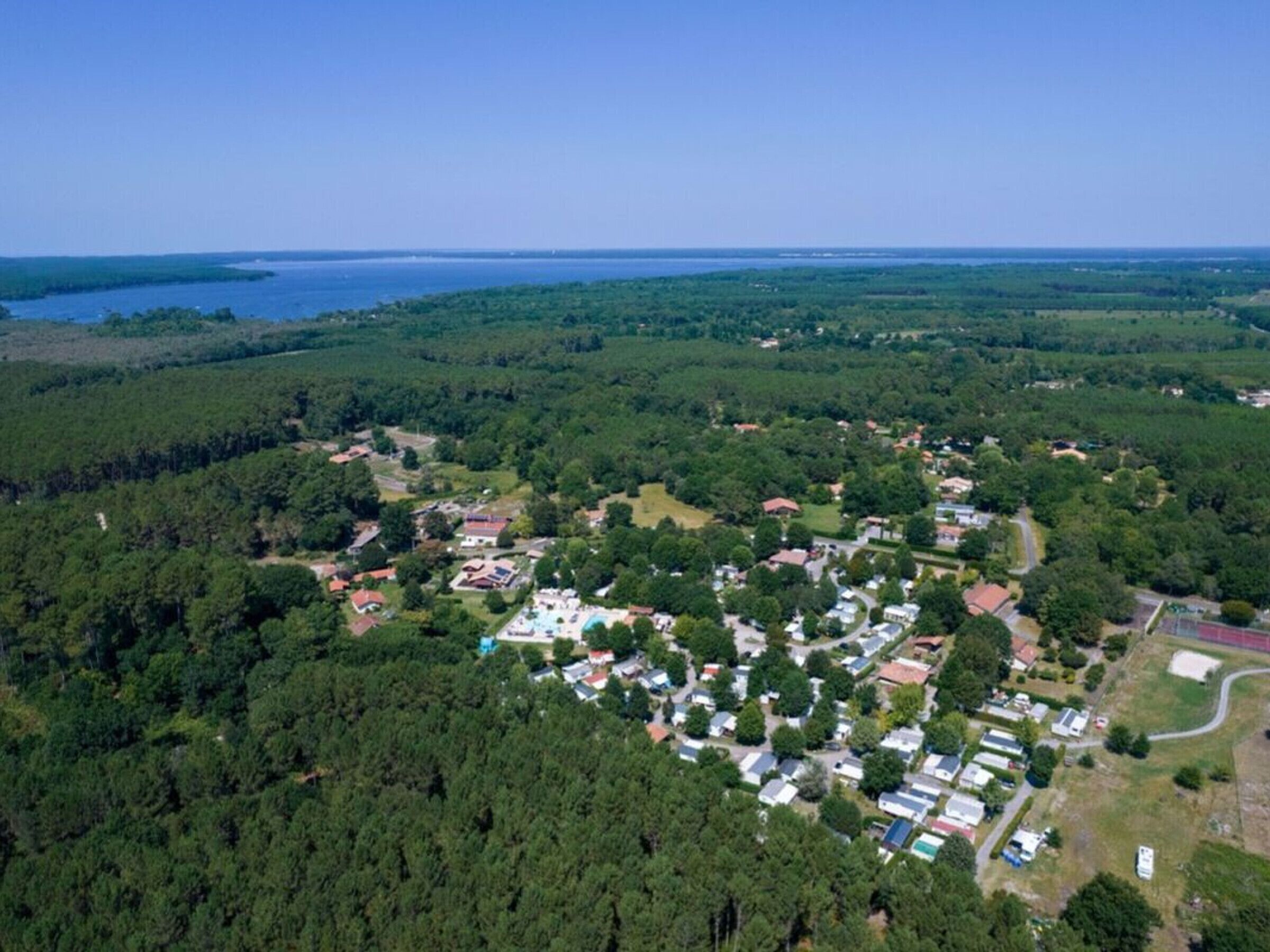 Vista aérea de uma área residencial com casas, piscina e paisagem arborizada.