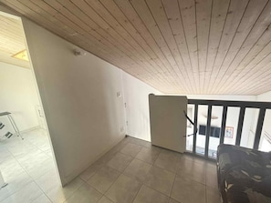 Ein Zimmer mit Holzboden, gefliestem Boden und einem schwarzen Geländer.