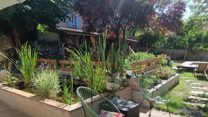 Un patio jardín con un pequeño estanque, muebles de madera y diversas plantas.
