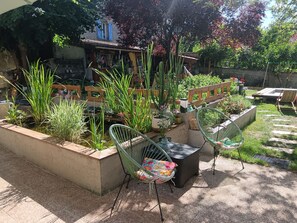 Une terrasse de jardin agrémentée d’un petit bassin, de meubles en bois et de diverses plantes.