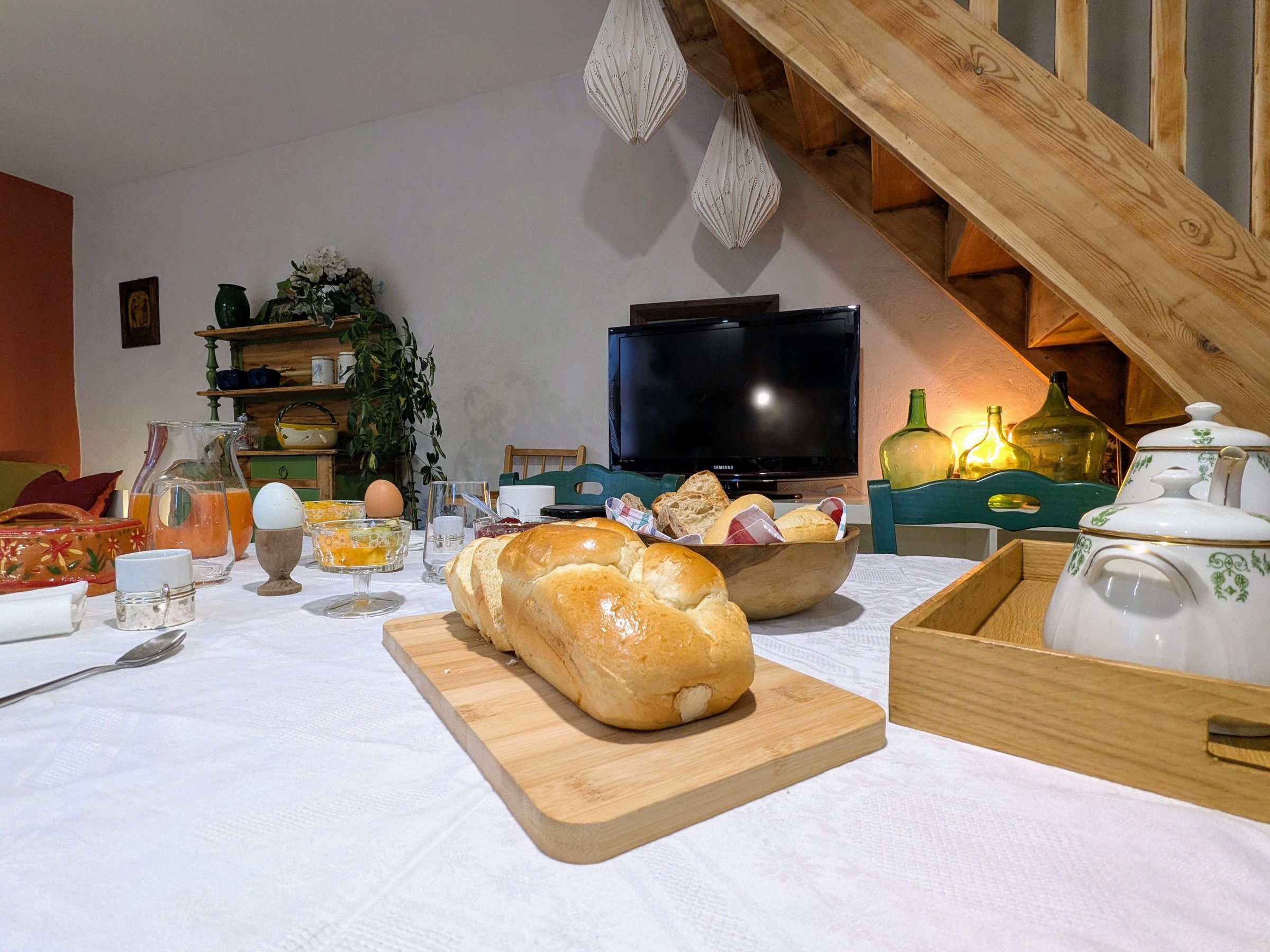 A dining table with bread, a bowl, and various kitchen items.