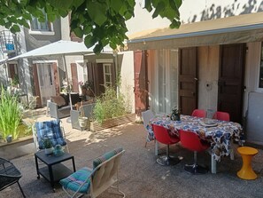 Un patio al aire libre con una mesa y sillas, una mesita auxiliar y un taburete amarillo.