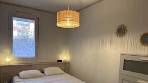 Makuuhuone, jossa on sänky, yöpöytälamput, ikkunasta avautuva näkymä, riippuvalaisin ja lipasto.