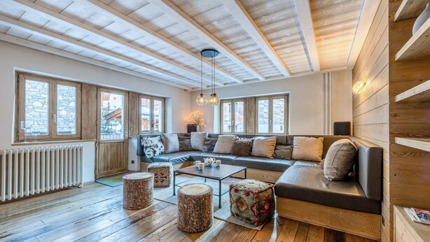 A cozy living room with a wooden ceiling, a large sofa, a coffee table, and a fireplace. - Charming apartment with sauna close to slopes (Val-d'Isère)