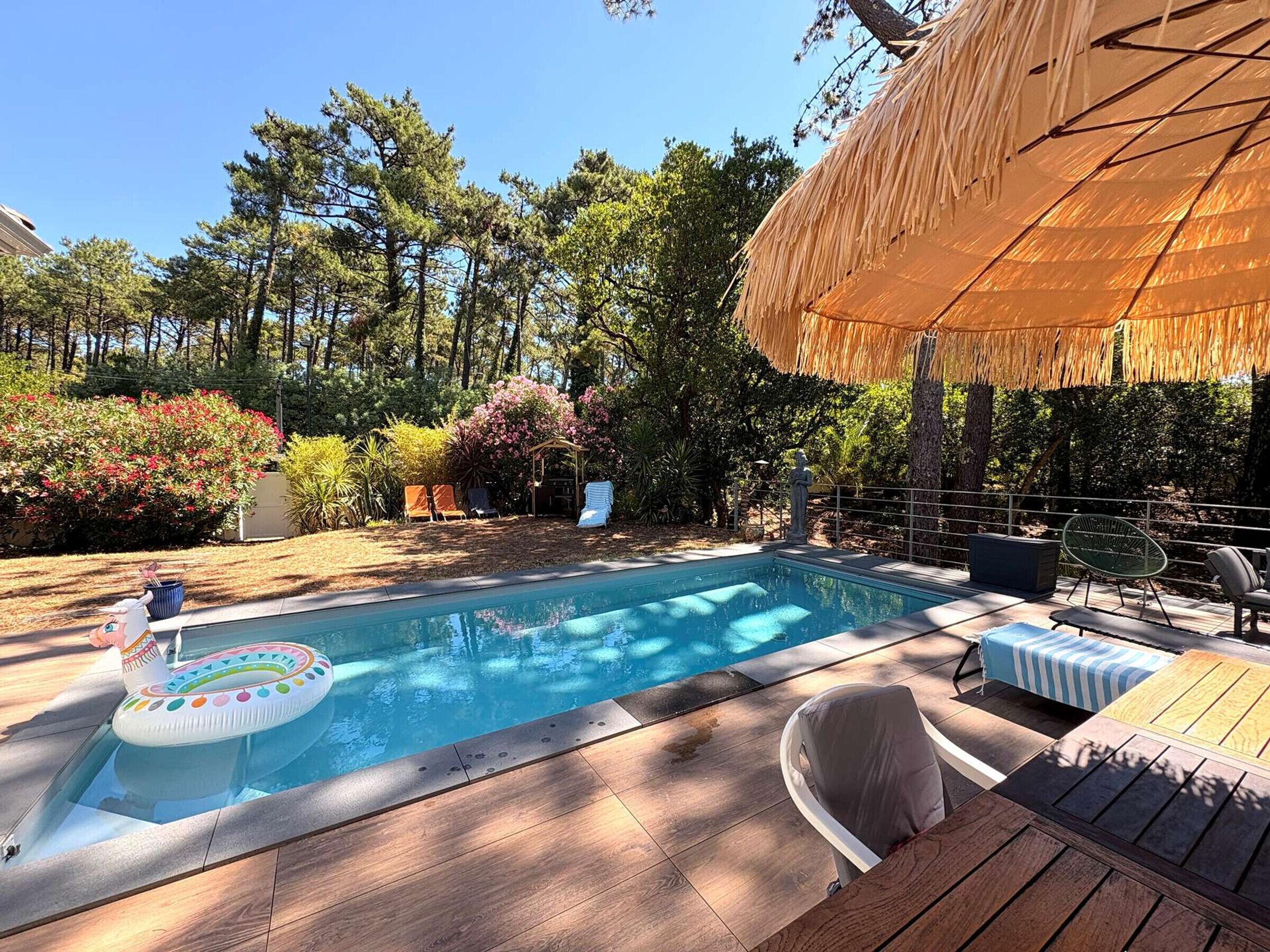 A swimming pool with a hot tub, lounge chairs, and a thatched umbrella.