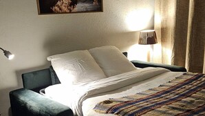 Ein Bett mit weißen Bettwäsche, einem dunkelgrünen Kopfteil und einer gestreiften Decke.