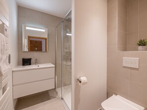 Une salle de bain moderne avec une douche à parois de verre, un lavabo blanc et un miroir au-dessus du lavabo.