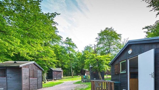 Un terrain de camping doté de cabanes en bois, d’un sentier de gravier et d’une terrasse en bois.