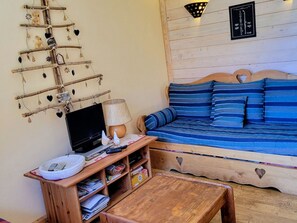 Een gezellige kamer met een houten bank, een televisie en een decoratie aan de muur.