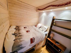 Een kamer met houten vloeren, een bed, een lamp op een plank en een klok aan de muur.