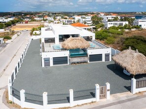 A modern building with a rooftop pool, a thatched-roof structure, and a gated entrance. - Penthouse mit Meerblick und Infinity-Pool Jan Thiel Curacao by Interhome (Jan Thiel)