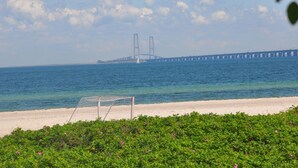 Une plage avec un but de football, un pont en arrière-plan et un ciel dégagé.