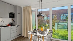 Cozinha moderna com área de refeições, janelas amplas e vista exterior.