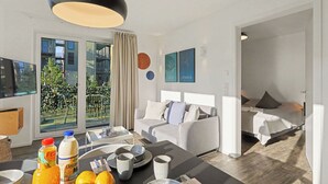 Quarto de hotel moderno com varanda, área de refeições com itens de café da manhã e cama com vista.
