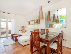 A modern living room with a glass dining table, wooden chairs, a sofa, and a large mirror. - Vacation home Tiana by Interhome (Tossa de Mar)