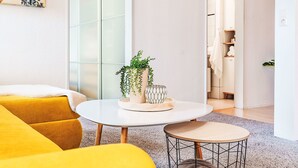 A modern living room with a yellow sofa, a round coffee table with decorative items, and a small side table.