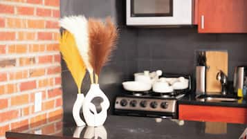 A kitchen with a black countertop, a white vase with feathers, a microwave, and a stove.