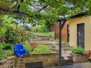A garden with a wooden bench, a blue chair, and a yellow building with a black door. - "Noreen" - 500m from the sea by Interhome (Faaborg)