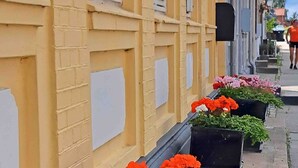 Un bâtiment jaune avec de nombreuses fenêtres et des jardinières sur le trottoir.