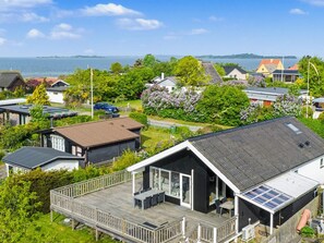 Ein Küstenwohngebiet mit Häusern, einer Holzterrasse und Blick aufs Meer.