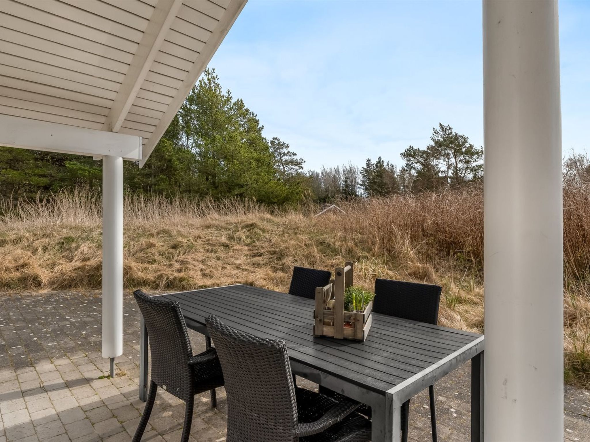 An outdoor patio with a table and chairs, surrounded by natural scenery.