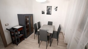 Et spiseområde med et bord, stole, et skab og en loftslampe.
