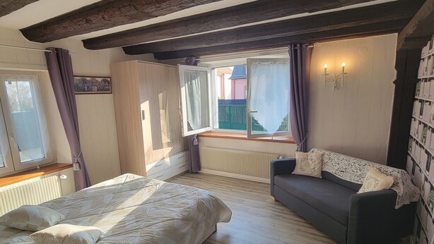 A bedroom with a large bed, a sofa, and a view of the outside.
