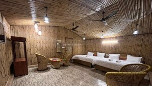 Ein Zimmer mit Holzboden, zwei Betten, Korbmöbeln und Deckenventilatoren.