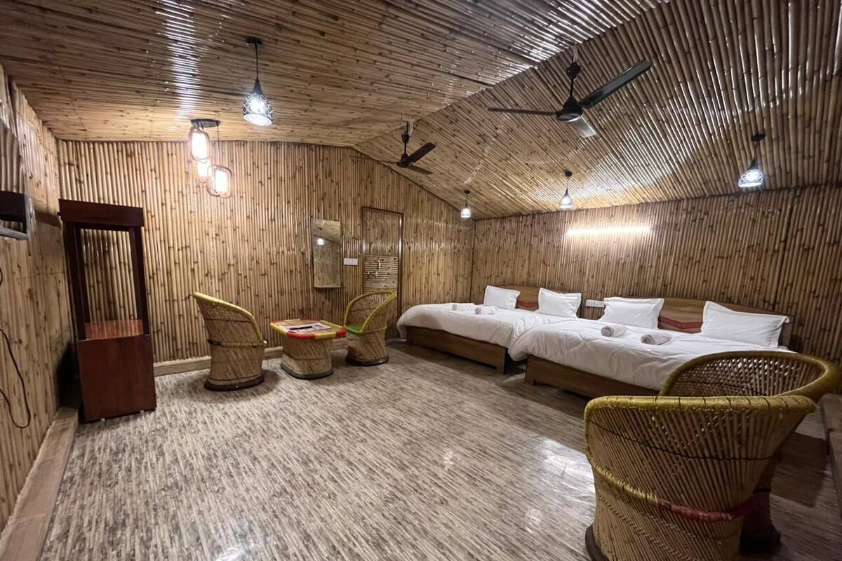 A room with a wooden ceiling, two beds, wicker furniture, and ceiling fans.