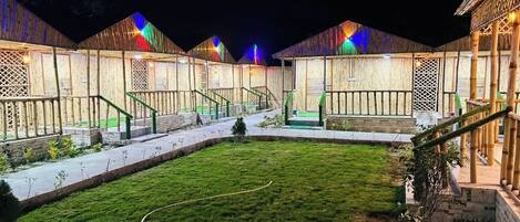 A series of wooden buildings with a central grassy courtyard, surrounded by pathways and staircases.